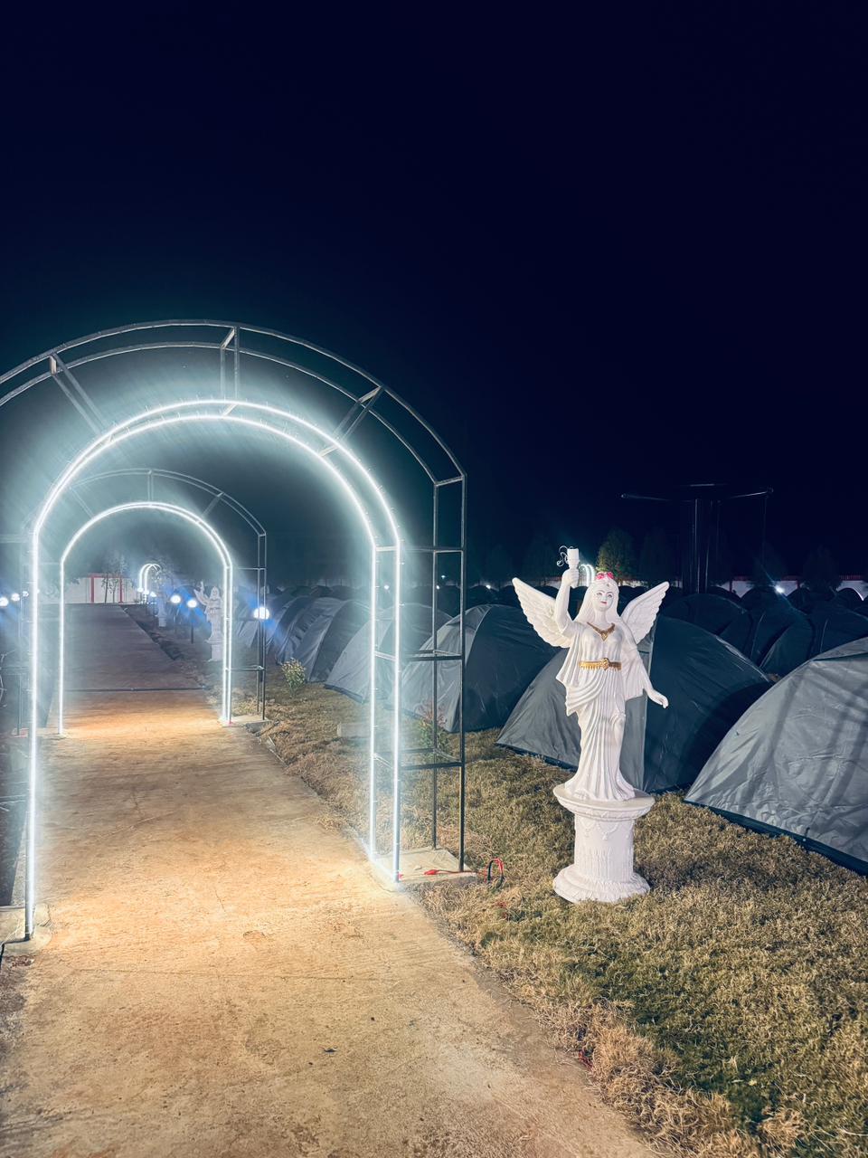 Glowing arch entrance to tent camp at night