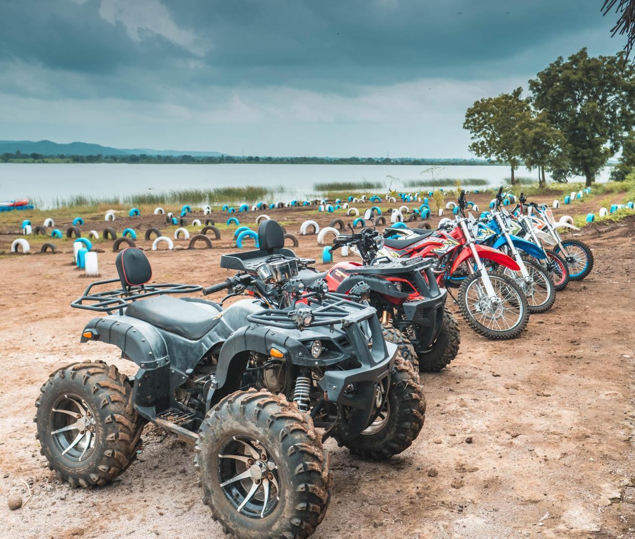 ATVs and dirt bikes lined up by the lake